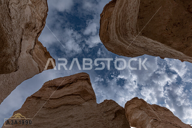 القمم والمرتفعات الجبلية في مدينة الاحساء، المعالم التاريخية الأثرية القديمة في المملكة العربية السعودية، منظر السماء الملبدة بالغيوم فوق التضاريس الطبيعية والتكوينات الصخرية في جبال المملكة، متحف أرض الحضارات في جبل القارة