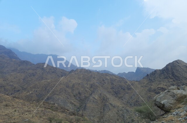 السماء الملبدة بالغيوم والسحب البيضاء, الطبيعة الصخرية لجبال السعودية, التضاريس في القمم الجبلية, التكوينات والتشكيلات الطبيعية الصخرية للمناطق المرتفعة, معالم سياحية مشهورة في مدينة الحجرة بمنطقة الباحة, السلاسل الجبلية وطرقات التنقل في المرتفعات