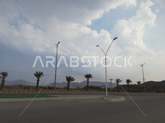 الأشجار والنباتات الخضراء المزروعة في طرقات المناطق المرتفعة, أعمدة الإنارة في شوارع المملكة العربية السعودية, المنتزهات والحدائق في مدينه الحجره بمنطقه الباحه, التضاريس والقمم والمرتفعات الجبلية في المناطق السياحية, السماء الملبدة بالغيوم والسحب البيضاء