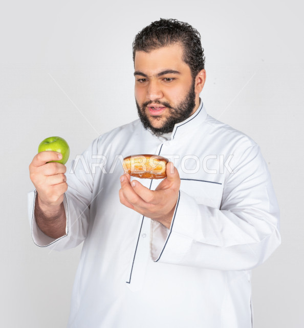 بورتريه شاب سعودي خليجي سمين في خيرة بين السكريات و الأكل الصحي ، يعاني من السمنة ، مشاكل صحية ،الوزن الزائد والسمنة ، خسارة السعرات الحرارية  ، اتباع نظام صحي
