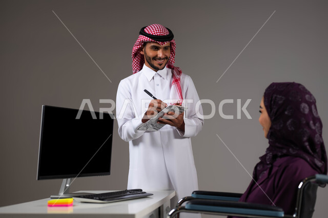 دمج العمل مع التقنية والتكنولوجيا، اتاحة الفرصة امام ذوي الهمم بالدخول الى مجال العمل، بورتريه مقرب لزميلين عربيين خليجيين سعوديين مبتسمين يقومان بإنجاز المهام عبر الحاسوب المحمول داخل المكتب، روح الفريق الواحد، تدوين الملاحظات لتطوير خطط الشركة، خلفيه رمادية