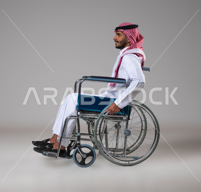 توفير اجهزة ومعدات تساعد بالحركة والتنقل، العنايه بأصحاب الهمم وتأمين احتياجاتهم الخاصة، بورتريه من الجانب لرجل مريض عربي سعودي خليجي من ذوي الاحتياجات الخاصه يجلس على كرسي متحرك، شعور المعاقين بالإنتماء والتقدير والإحترام في السعوديه، خلفيه رمادية