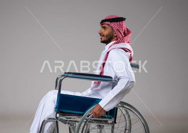 Providing devices and equipment that assist with movement and mobility, taking care of people of determination and ensuring their special needs, a portrait from the side of a sick Saudi Arab Gulf man with special needs sitting in a wheelchair, the feeling of belonging, appreciation and respect for disabled people in Saudi Arabia, gray background