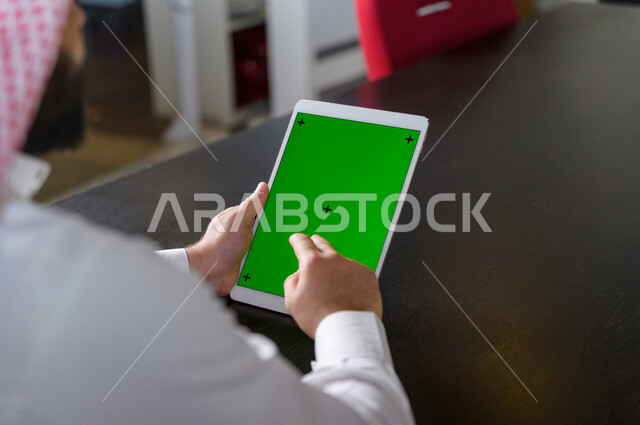 A Saudi Gulf businessman using a tablet with a green screen, chroma, technology and computer, remote purchase, distance education, video games