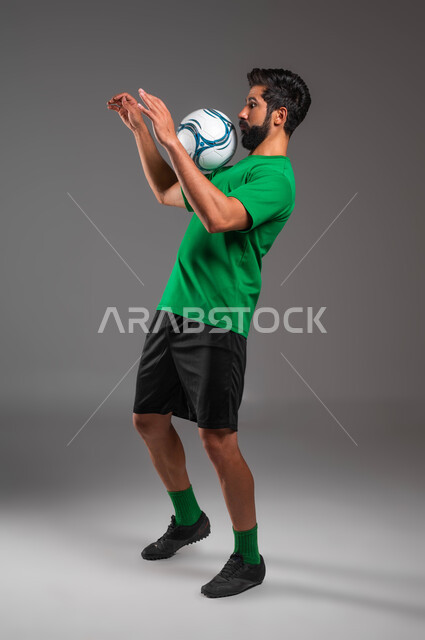 فنون ومهارات اللعب، احتراف التعامل مع كرة القدم، بورتريه للاعب عربي سعودي خليجي يرتدي الملابس الرياضية يلعب بالكرة، حركات الحماس والاستعداد لبدء المباراة، صورة الجسم بالطول الكامل، خلفية رمادية .