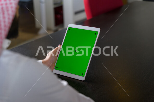 رجل أعمال سعودي خليجي يستخدام جهاز لوحي تابلت بشاشة خضراء كروما ، تقنية و حاسب ، شراء عن بعد ، التعليم عن بعد ، العاب فيديو