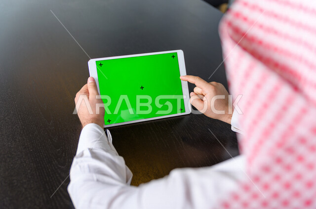 رجل أعمال سعودي خليجي يستخدام جهاز لوحي تابلت بشاشة خضراء كروما ، تقنية و حاسب ، شراء عن بعد ، التعليم عن بعد ، العاب فيديو