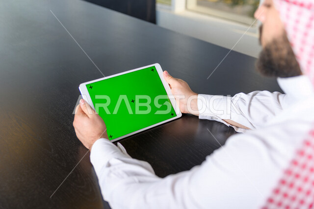 رجل أعمال سعودي خليجي يستخدام جهاز لوحي تابلت بشاشة خضراء كروما ، تقنية و حاسب ، شراء عن بعد ، التعليم عن بعد ، العاب فيديو
