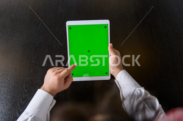 رجل أعمال سعودي خليجي يستخدام جهاز لوحي تابلت بشاشة خضراء كروما ، تقنية و حاسب ، شراء عن بعد ، التعليم عن بعد ، العاب فيديو