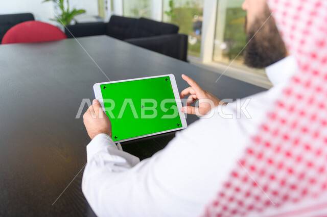 رجل أعمال سعودي خليجي يستخدام جهاز لوحي تابلت بشاشة خضراء كروما ، تقنية و حاسب ، شراء عن بعد ، التعليم عن بعد ، العاب فيديو