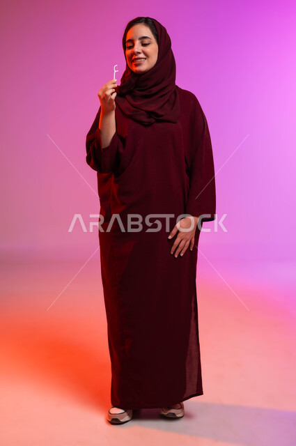 العناية بالصحة الفموية، الاهتمام بالأناقة والمظهر الخارجي، التأكد من نظافة الأسنان بعد تناول الطعام، المحافظة على ابتسامة بيضاء، بورتريه لامرأة عربية خليجية سعودية تمسك بيدها الخيط السني بإيماءات الاعجاب، صورة الجسم بالكامل، خلفية ملونة