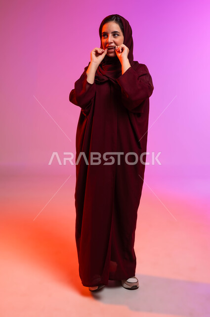 التأكد من نظافة الأسنان بعد تناول الطعام، الاهتمام بالأناقة والمظهر الخارجي، المحافظة على ابتسامة بيضاء، بورتريه لامرأة عربية خليجية سعودية تقوم بتنظيف أسنانها باستخدام الخيط السني، مفهوم العناية بصحة الفم، صورة الجسم بالكامل، خلفية ملونة