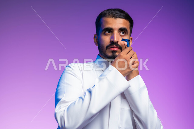 مفهوم العناية بالبشرة والاهتمام بالمظهر الخارجي، المحافظة على الأناقة والنظافة الشخصية، بورتريه مقرب لرجل عربي خليجي سعودي يرتدي الثوب التقليدي يقوم بإزالة شعر الوجه باستخدام شفرة الحلاقة الرجالية بإيماءات التمعن والتركيز، خلفية ملونة