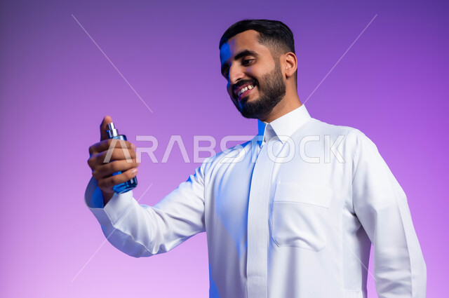 عطورات خليجية سعودية, التسويق لمنتجات العطور, مفهوم التعطر والتطيب, استخدام الزيوت العطرية الطبيعية, بورتريه مقرب لرجل عربي خليجي سعودي يرتدي الثوب التقليدي يقوم برش العطر, خلفية ملونة
