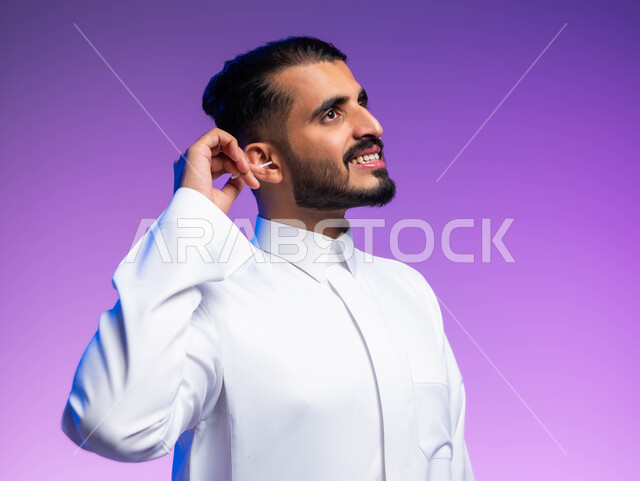 استخدام أعواد ونكاشات القطن، روتين نظافة الأذنين اليومية، بورتريه مقرب لرجل عربي خليجي سعودي يقوم بتنظيف أذنه بنكاشة قطنية ( مسحة قطنيه )، مفهوم العناية والاهتمام بصحة ونظافة الأذن، خلفية ملونة