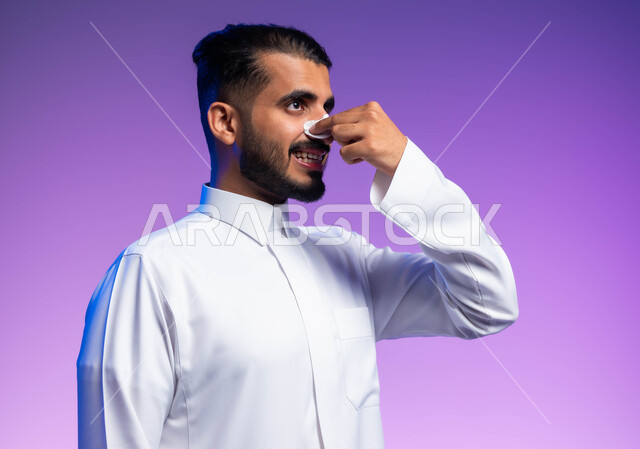 التخلص من الرؤوس السوداء والجلد الميت، استخدام ماسكات تنظيف المسام ومكونات تجميلية، بورتريه مقرب لرجل عربي خليجي سعودي يرتدي الثوب التقليدي يضع لصقات الأنف، مفهوم العناية والاهتمام بنضارة وتحسين البشرة، خلفية ملونة