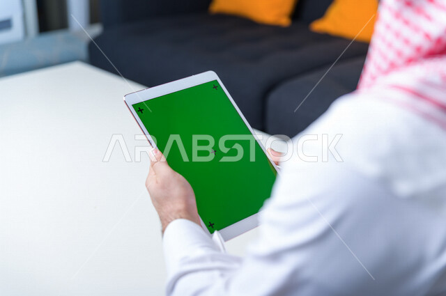 رجل أعمال سعودي خليجي يستخدام جهاز لوحي تابلت بشاشة خضراء كروما ، تقنية و حاسب ، شراء عن بعد ، التعليم عن بعد ، العاب فيديو