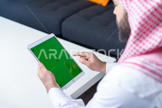 رجل أعمال سعودي خليجي يستخدام جهاز لوحي تابلت بشاشة خضراء كروما ، تقنية و حاسب ، شراء عن بعد ، التعليم عن بعد ، العاب فيديو