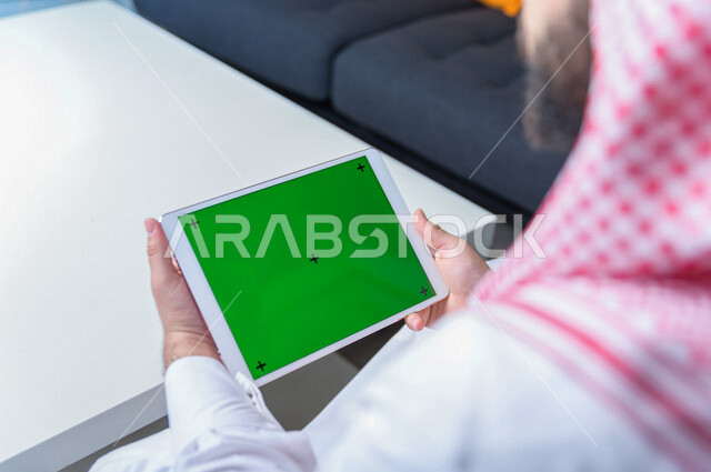 رجل أعمال سعودي خليجي يستخدام جهاز لوحي تابلت بشاشة خضراء كروما ، تقنية و حاسب ، شراء عن بعد ، التعليم عن بعد ، العاب فيديو