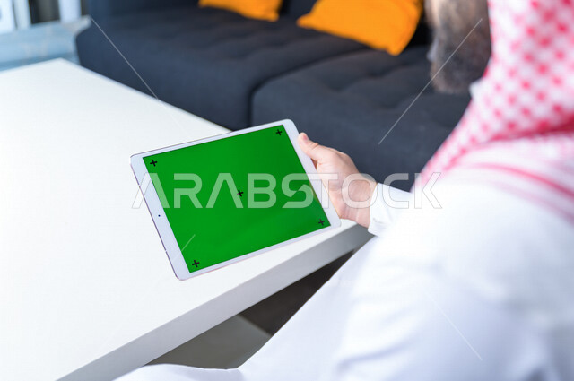 رجل أعمال سعودي خليجي يستخدام جهاز لوحي تابلت بشاشة خضراء كروما ، تقنية و حاسب ، شراء عن بعد ، التعليم عن بعد ، العاب فيديو