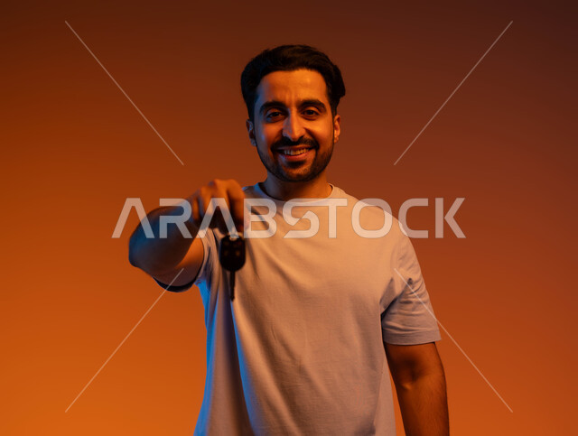 خدمة صف السيارة بالمواقف الخاصة, اقتناء سيارة جديدة بإيماءات السرور, الحصول على رخصة قيادة, بورتريه مقرب لشاب عربي خليجي سعودي مبتسم يرتدي الزي الكاجوال يمسك بيده مفتاح السيارة وينظر إلى الكاميرا, استلام وتسليم المفاتيح, خلفية ملونة