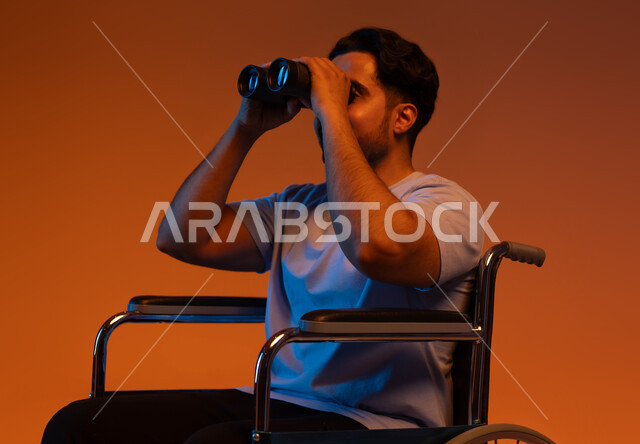 Love of exploration and adventure, future planning for goals and ambitions, a future vision for people of determination, a portrait of a crippled Saudi Arabian Gulf man wearing a casual outfit sitting in a wheelchair and holding binoculars in his hand, a colored backgroun .d.