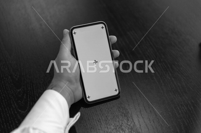 رجل أعمال سعودي خليجي يستخدام هاتفه المحمول بخلفية خضراء كروما ، تقنية و حاسب ، استخدام تقنية السمارت على الهاتف المحمول ليتحكم بالتلفاز