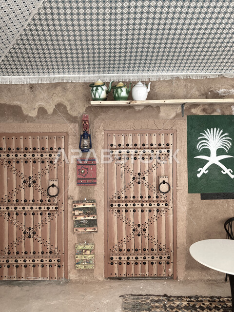 Historical villages and cities, ancient Arab architectural design for ancient antique wooden doors, a wooden door for a mud house, heritage places in the Kingdom of Saudi Arabia, a metal lantern hanging on the mud walls