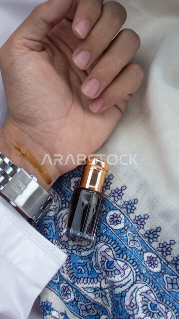 استخدام تولة العود للتبخر والتعطر بالزيوت الطبيعيه والمسك ،صورة مقربة ليد رجل عربي خليجي سعودي يضع على يده العطر ،التسويق لمنتجات العود والبخور, منتج محلي سعودي صنع في السعودية