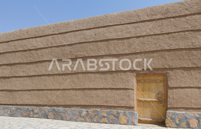 الطراز المعماري التاريخي في المملكة العربية السعودية، أماكن سياحية أثرية ثقافية، صورة مقربة لباب خشبي قديم والجدران الطينية التراثية في قرية أشيقر في الرياض, معالم ومناطق متميزة لجذب واستقطاب السائحين من العالم .