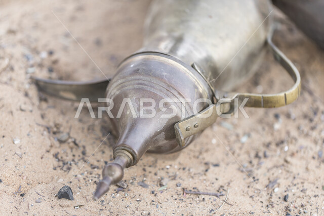 جلسات بر عربية شرقية، صورة مقربة لدلة قهوة عربية نحاسية على الرمال الذهبية الناعمة في صحراء المملكة العربية السعودية ،مفهوم الضيافة عند العرب، تقديم المشروبات الساخنة