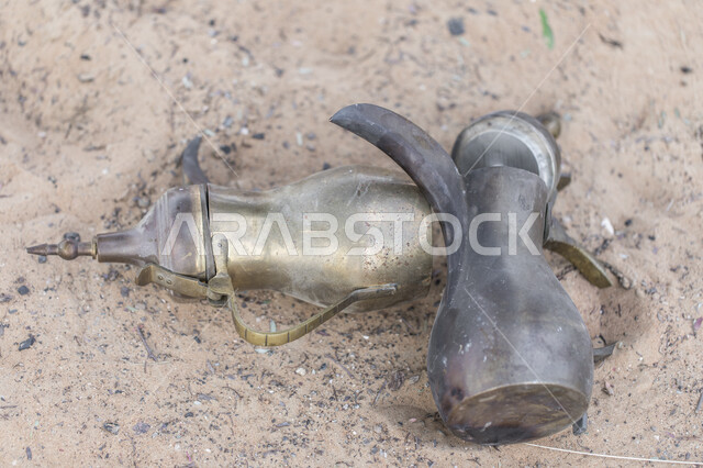 دلة قهوة عربية نحاسية على الرمال الذهبية الناعمة في صحراء المملكة العربية السعودية ،مفهوم الضيافة عند العرب، جلسات بر عربية شرقية، تقديم المشروبات الساخنة