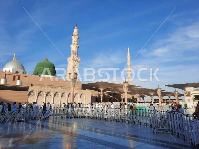 The green dome and minaret of the Prophet’s Mosque, religious landmarks in the Kingdom, worship and closeness to God, holy Islamic places, Muslims gathered in the outer complex of the Prophet’s Mosque in Medina, Kingdom of Saudi Arabia