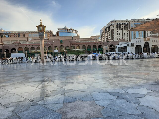 Distinct religious landmarks in Medina, Muslims gathered in the courtyard of the Prophet’s Mosque in the Kingdom of Saudi Arabia, holy Islamic places, attention to the cleanliness of the marble floor in the outer complex of the mosque, worship and getting closer to God, the Hajj and Umrah season
