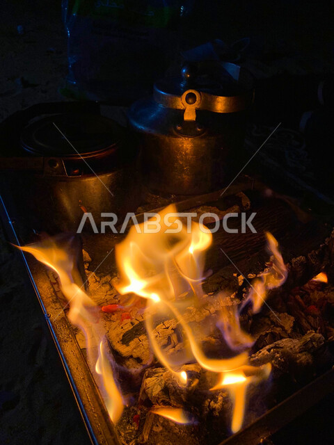 Camping in the wilds of Al-Qassim, a close-up of preparing tea on a fire of firewood, burning tree wood, trips and wild kashta, the winter weather in the desert of the Kingdom of Saudi Arabia, preparing hot drinks in the cold winter weather