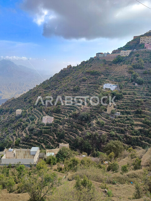  البيوت والمباني السكنية الاثرية القديمة في جبال محافظة فيفاء في جازان، المدرجات الزراعية الخضراء والاشجار على القمم والمرتفعات الجبلية، معالم وأماكن سياحية طبيعية في المملكة العربية السعودية، منظر السماء المليئة بالغيوم البيضاء، خلفية الطبيعة 