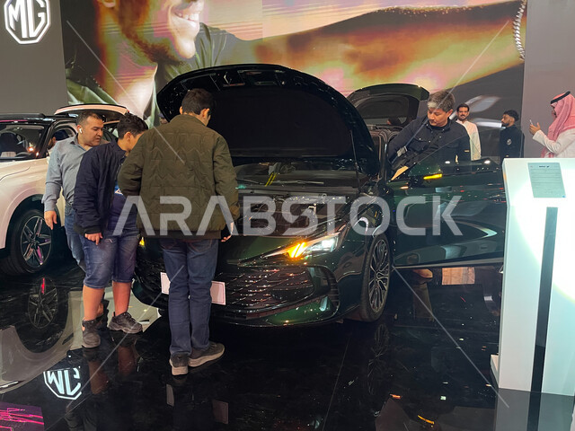 Tourists enjoy seeing and examining modern, advanced electric cars in ...