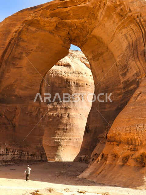 Rock formations and formations in the desert areas of the Kingdom of Saudi Arabia, a Saudi Arabian Gulf man contemplating the natural landscape of the mountain peaks and heights in Al-Ula Governorate, ancient historical monuments, famous tourist places in Saudi Arabia
