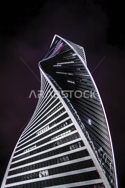 صورة مقربة بزاوية من الأسفل للبرج المجدول المضاء ليلا في المملكة العربية السعودية، الفن الهندسي المعماري لناطحات السحاب في مدينة الرياض، أبراج ومعالم مشهورة
