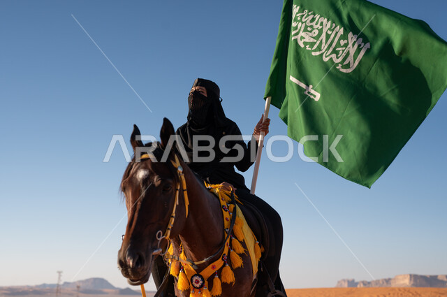  رفع راية وعلم السعودية في الصحراء، تأسيس الدولة السعودية الأولى 22 فبراير، أنشطة وفعاليات ركوب الأحصنة، إمرأة عربيه خليجية ترتدي البرقع والعباءة تمتطي فرسها البني في وضح النهار، ممارسة هواية ركوب الخيل, حب الفروسيه وركوب الجياد، الاحتفال بيوم العلم السعودي