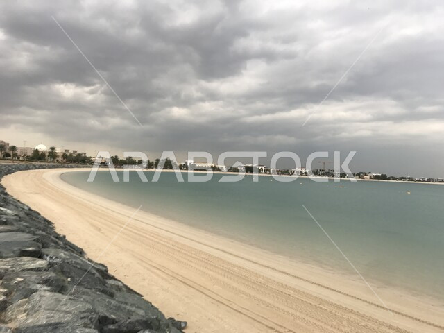 الطبيعة البحرية الساحلية, إطلالة متميزة على كورنيش الممزر السياحي في إمارة دبي في وضع النهار، الواجهة البحرية الرومانسية في الإمارات العربية المتحدة، الاهتمام بزراعة أشجار النخيل, منظر السماء المليئة بالغيوم .