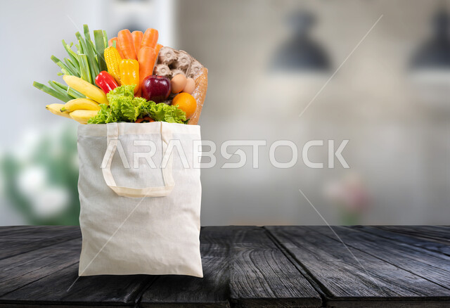 التسوق وشراء الاحتياجات و المنتجات والمواد الغذائية اللازمة للمستهلك, مفهوم الغذاء الصحي، صورة مقربة لكيس قماشي مليئ بالخضراوات والفواكه المتنوعه على قاعدة خشبية