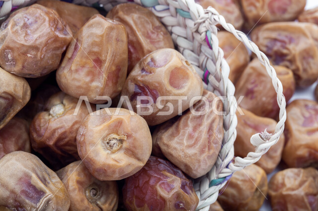 حصاد النخيل في مزارع المملكة، ضيافة رمضانية شهية، الأنواع المختلفة من التمور الصحية اللذيذة، وجبة غذائية صحية ذات أهمية عاليه، منتجات محلية سعودية وطنية، صورة مقربة لحبات التمر في سلة من القش، خلفية بيضاء 