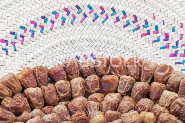 صورة مقربة لحبات التمر في طبق من القش، منتجات محلية سعودية وطنية، حصاد النخيل في مزارع المملكة، ضيافة رمضانية شهية، الأنواع المختلفة من التمور الصحية اللذيذة، وجبة غذائية صحية ذات أهمية عاليه، خلفية بيضاء 