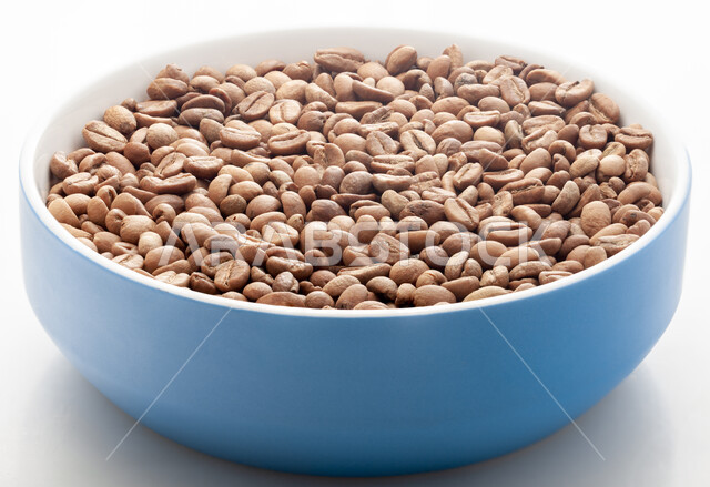 Preparing and preparing fresh coffee, the quality of national food industries and crops in the Kingdom of Saudi Arabia, making delicious hot drinks from coffee beans, a close-up of a blue pot filled with brown roasted coffee seeds and beans, white background.