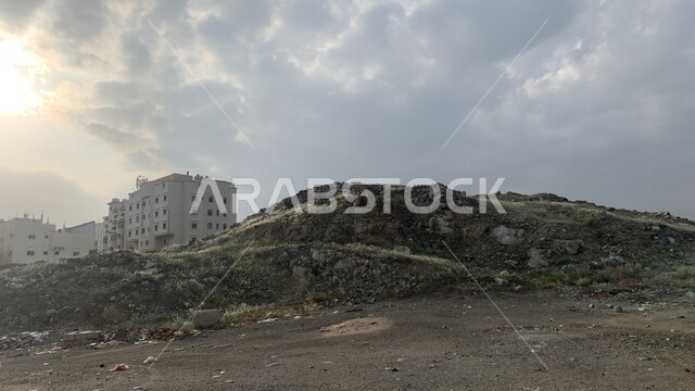 تلال الردم ومخلفات البناء, صورة مقربة لتجمعات الحجار والرمال في مكة المكرمة، معالم واماكن سياحية مشهورة, المباني السكنية في المملكة العربية السعودية, منظر السماء التي تعج بالغيوم.