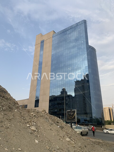 Backfill hills and construction waste, a close-up of the Commercial Bank building in Mecca, famous landmarks and tourist places, modern-style architecture in the Kingdom of Saudi Arabia, a view of the clear sky