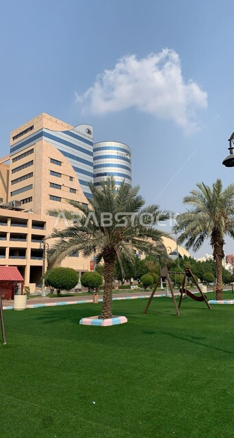 الاهتمام في زراعه الاشجار والنباتات الخضراء,  الفنون والتصاميم الهندسية المعمارية المميزة للأبراج وناطحات السحاب، بناء الاهله مول في حي الرصيفة في مدينة مكة المكرمة قي وقت النهار، منظر السماء المليئة بالغيوم البيضاء، أماكن و معالم سياحية مشهورة