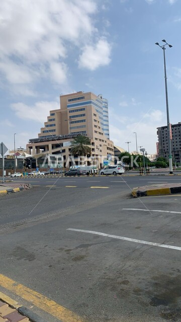 Paved roads and streets, distinctive architectural arts and designs for towers and skyscrapers, construction of Al Ahla Mall in the Rusaifah neighborhood in the city of Mecca during the day, the view of the sky filled with white clouds, famous tourist places and landmarks