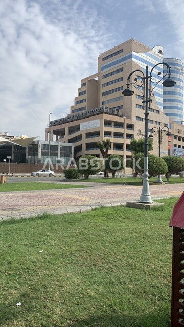 Urban development and growth, famous tourist attractions, interest in planting trees and green plants, arts and architectural designs for towers and skyscrapers in Saudi Arabia, the Al Ahla Mall tower in the Rusaifah neighborhood in Mecca, the background of the sky full of white clouds